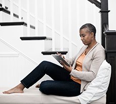 woman sitting on stairs looking at Vetron on a tablet